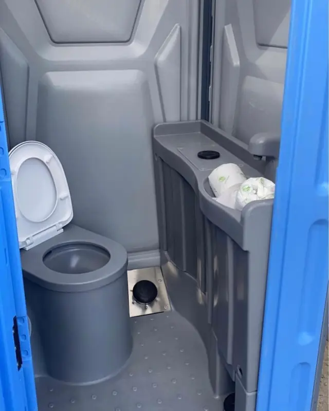Inside a deluxe porta potty with a foot-pump sink, mirror and paper towels
