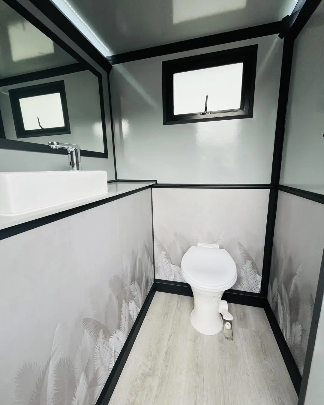 Inside a restroom trailer stall with flushing toilet and sink