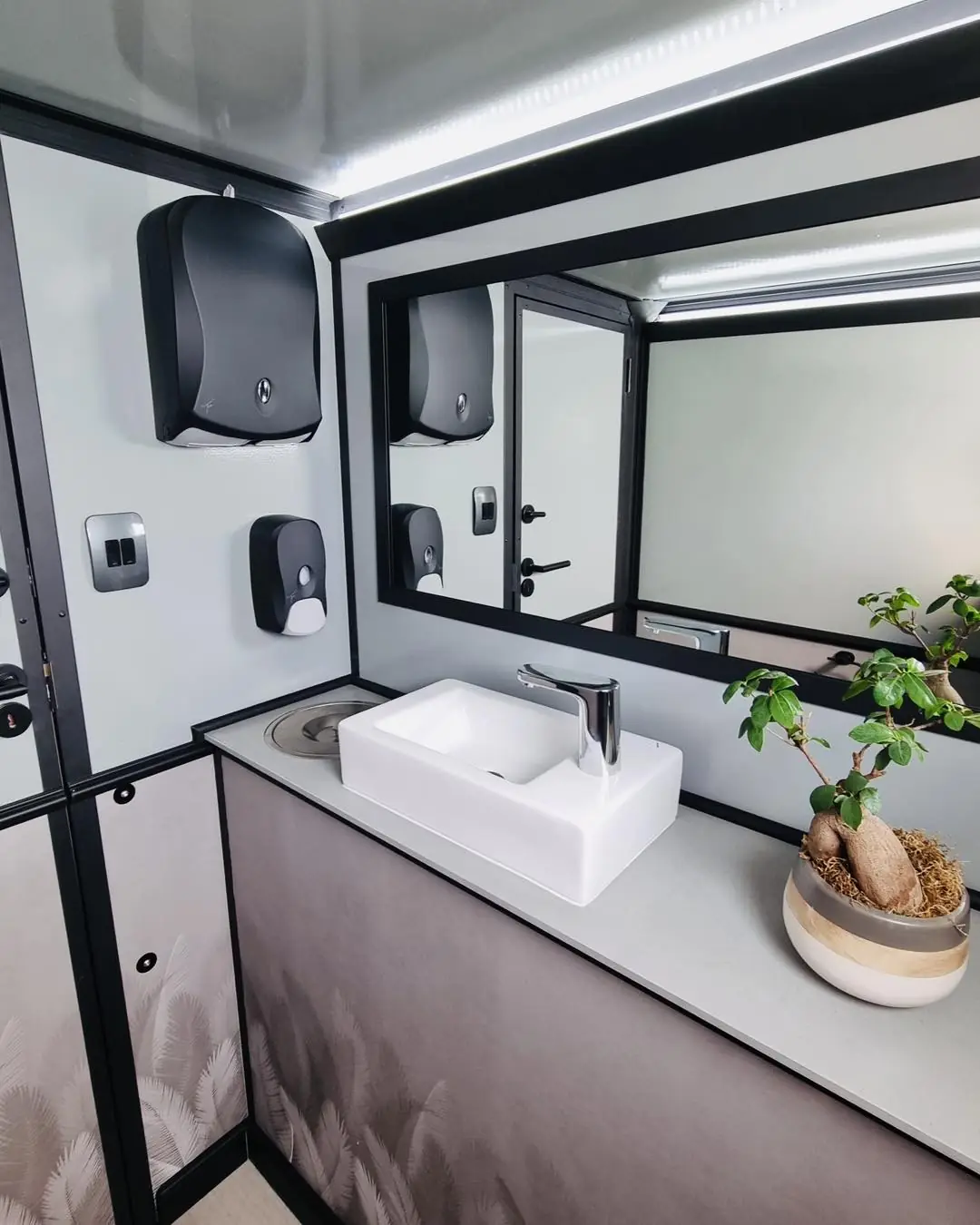 Vanity sink and mirror inside a restroom trailer stall