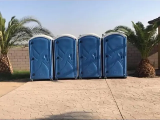 Four blue standard porta potties lined up for a large outdoor event