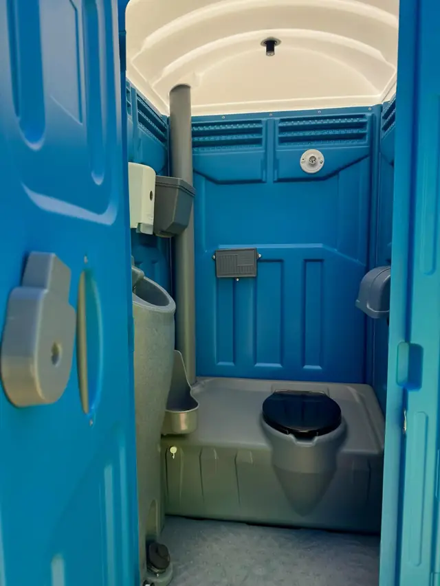 Inside a standard porta potty with the toilet seat, urinal and paper holder