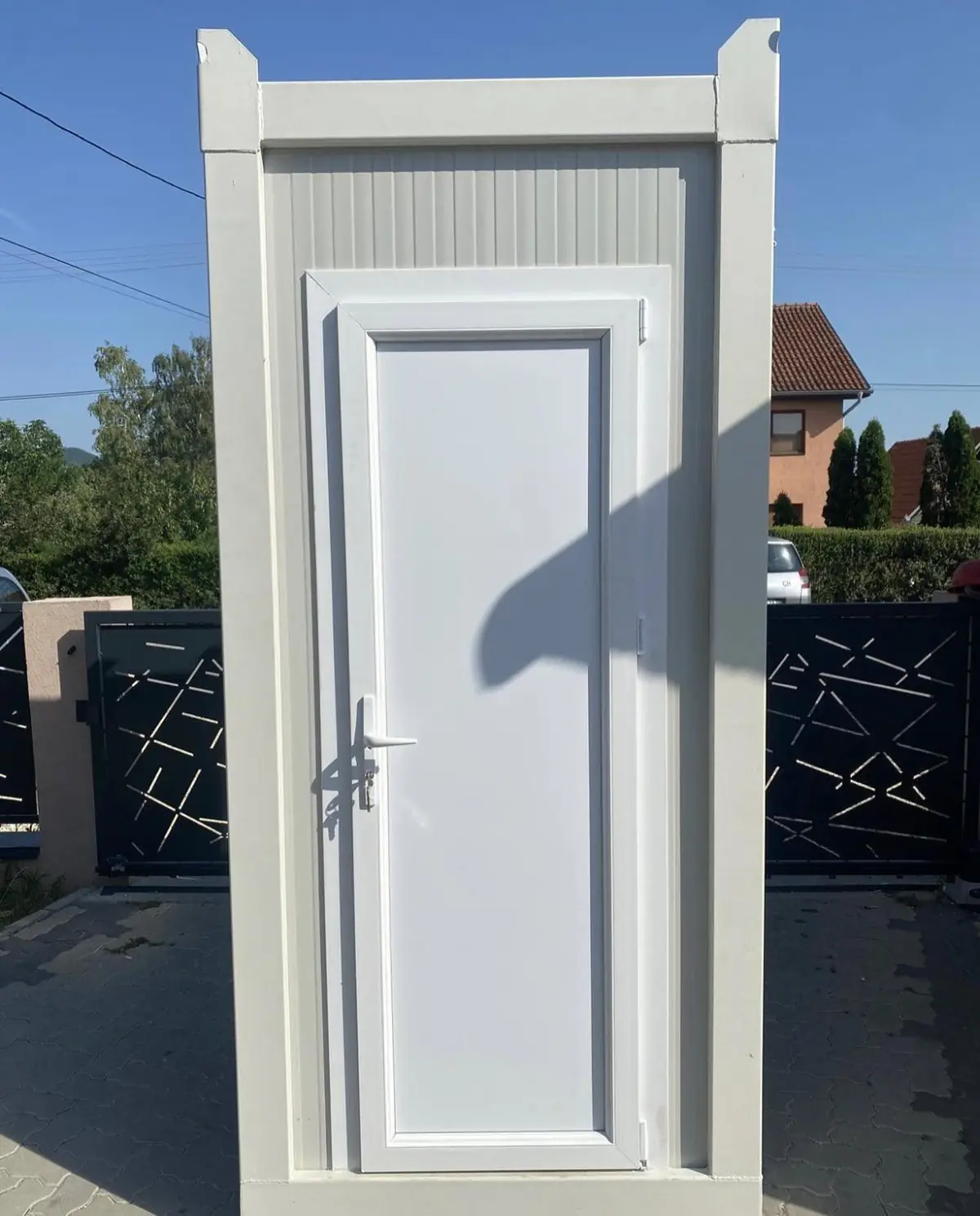 A white single-room flushing restroom cabin set on level ground